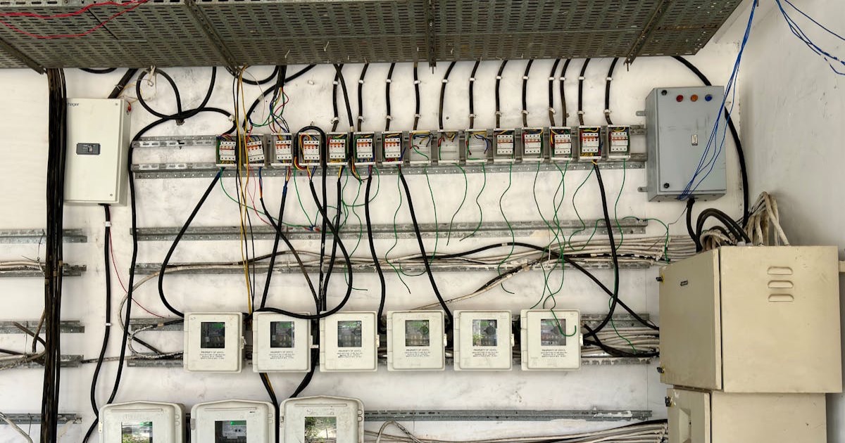 Complex network of electrical wiring and control panels in an industrial setting.