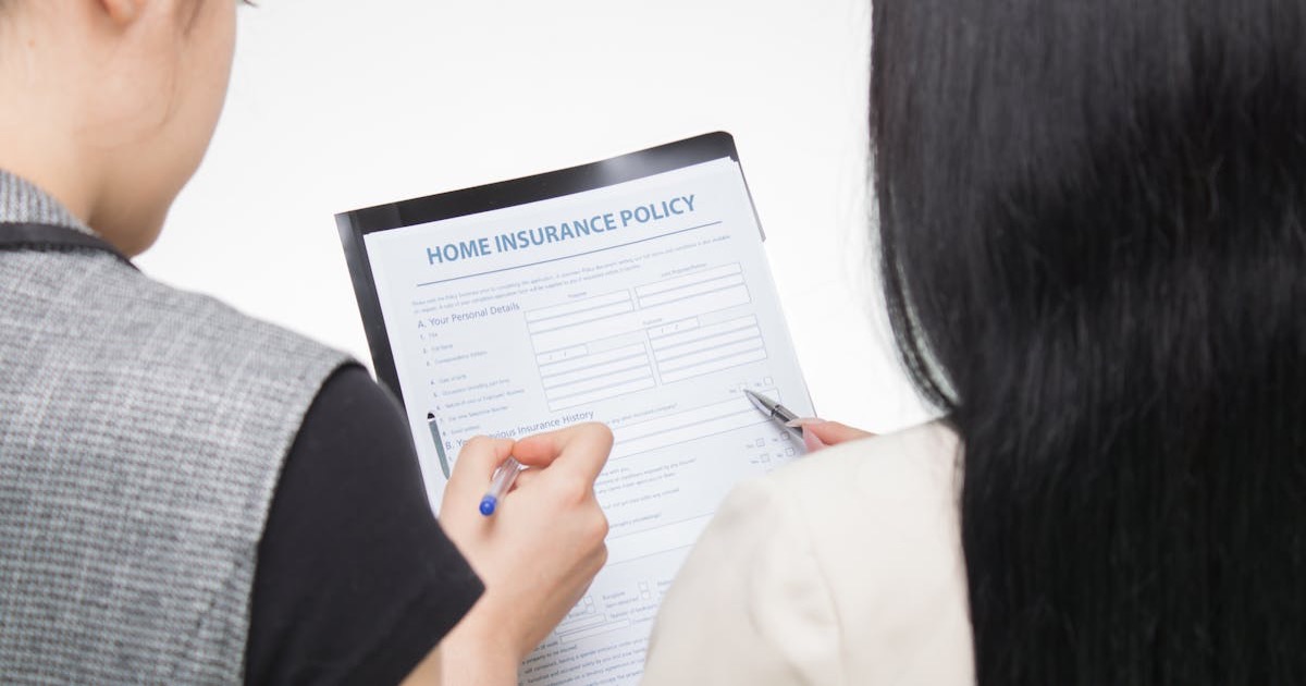 Two women examining home insurance policy form, focused on details.