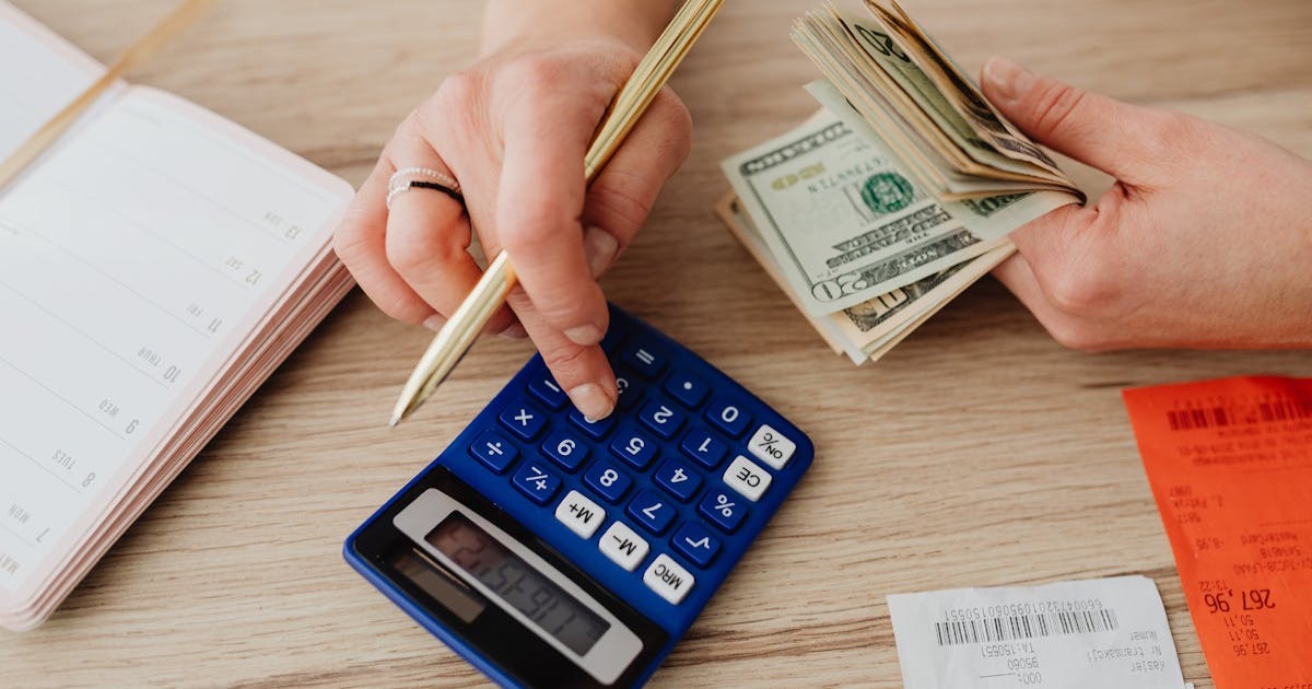 Hands handling cash and calculator for budget planning. Modern financial scene.