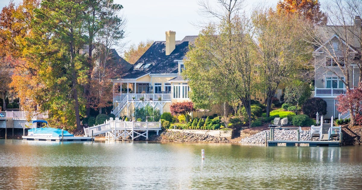Picturesque lakeside home surrounded by vibrant autumn foliage. Ideal for real estate or travel themes.