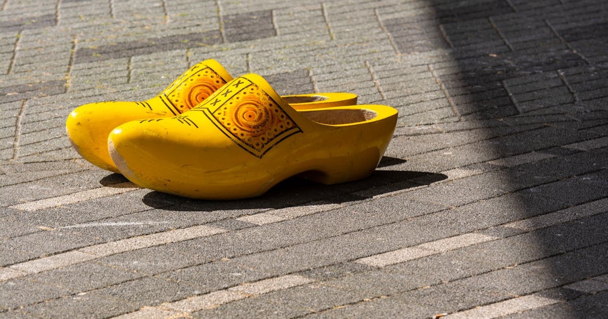 Bright yellow traditional Dutch clogs on a sunlit cobblestone pathway.